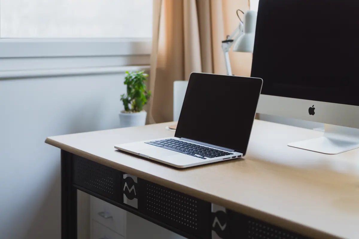 An open laptop on a tidy desk beside a desktop computer