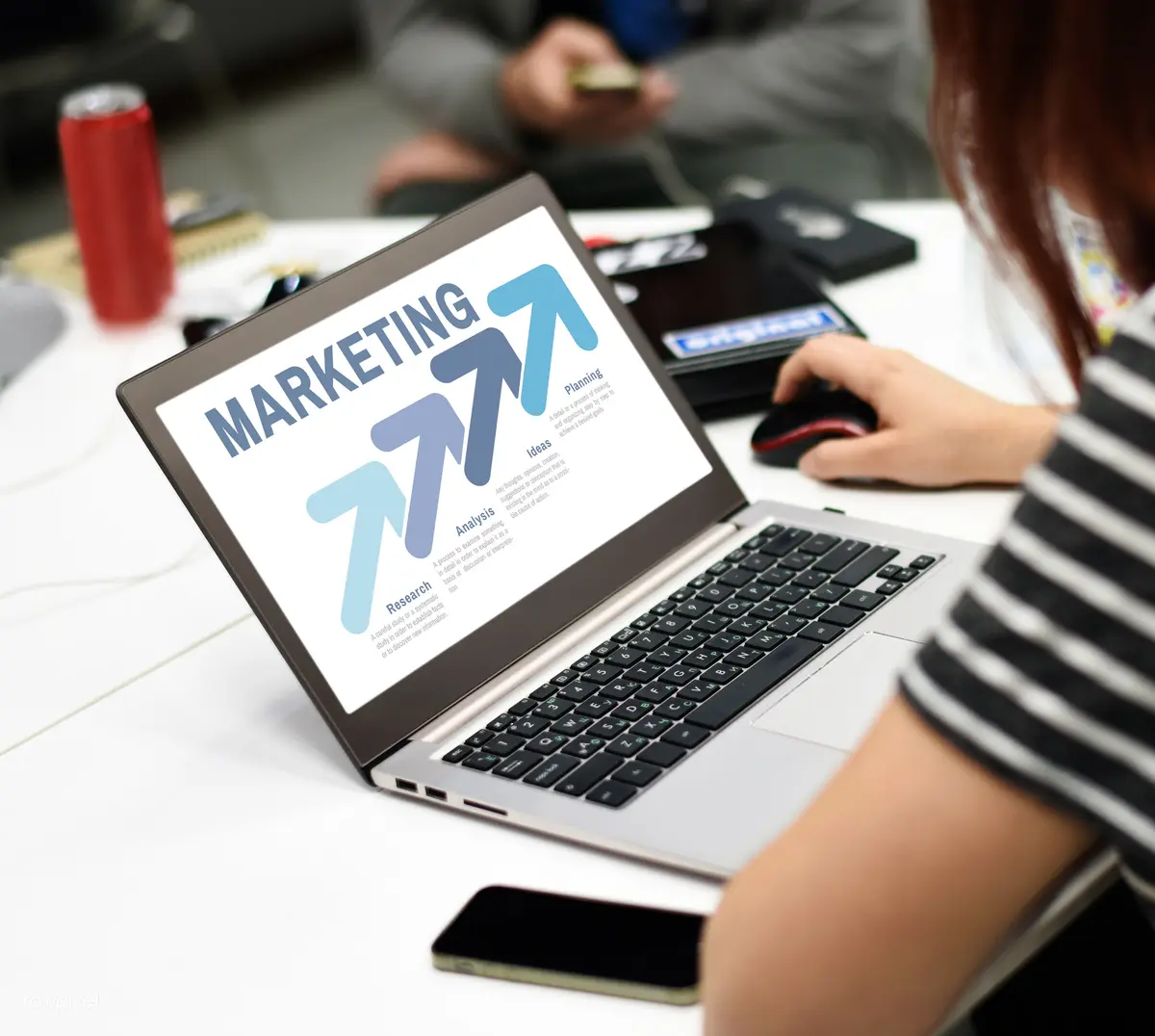 A person using a laptop displaying a marketing planning graphic at a shared table